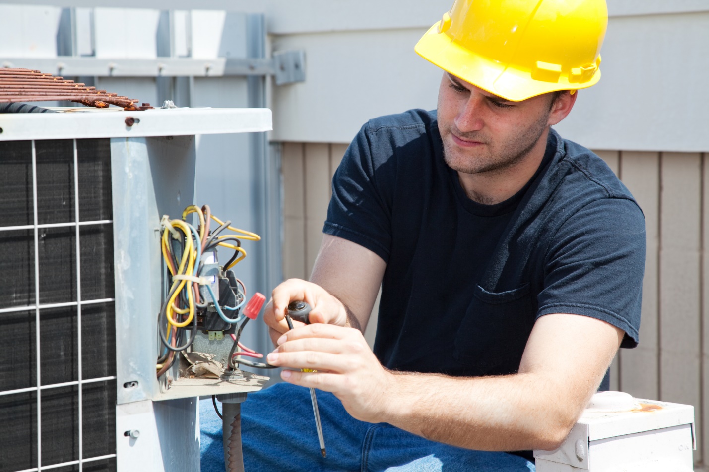 A person wearing a hard hat working on an electrical box

Description automatically generated