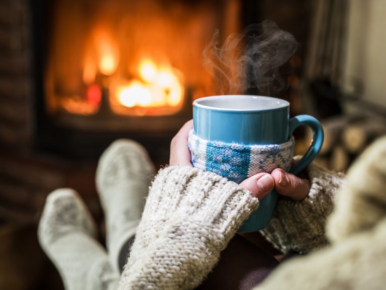 Person with mug sitting near fireplace