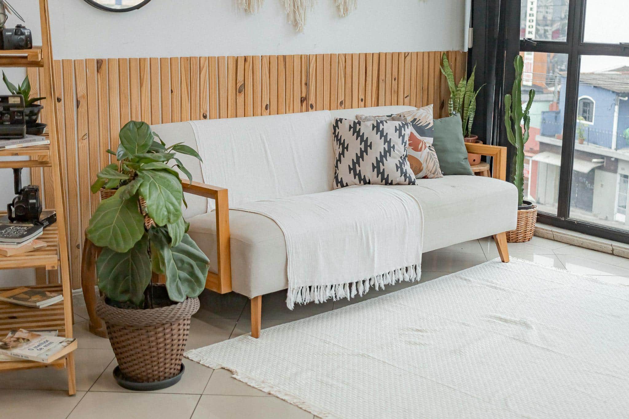 Couch and potted plants set against wall lined with wooden planks