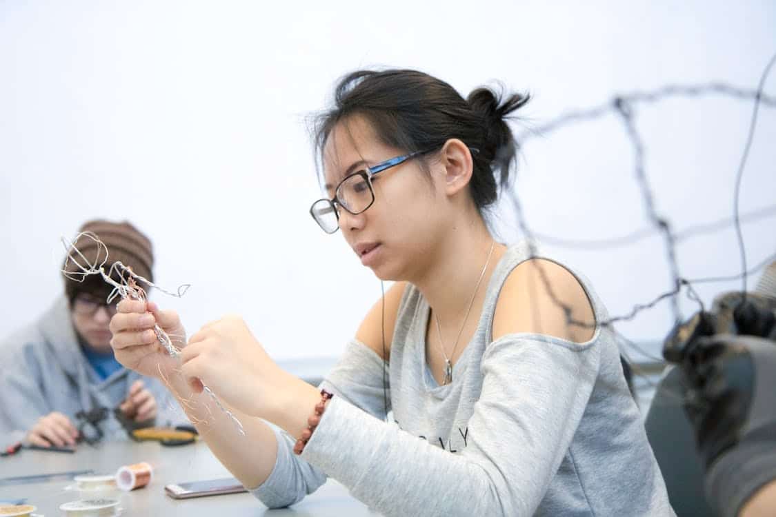 Free Focused young woman working on intricate wire sculpture in a creative workshop. Artistic expression and skill. Stock Photo