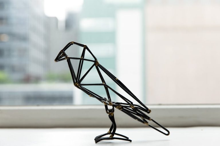 Free Wire bird sculpture captured on a windowsill with cityscape background. Stock Photo