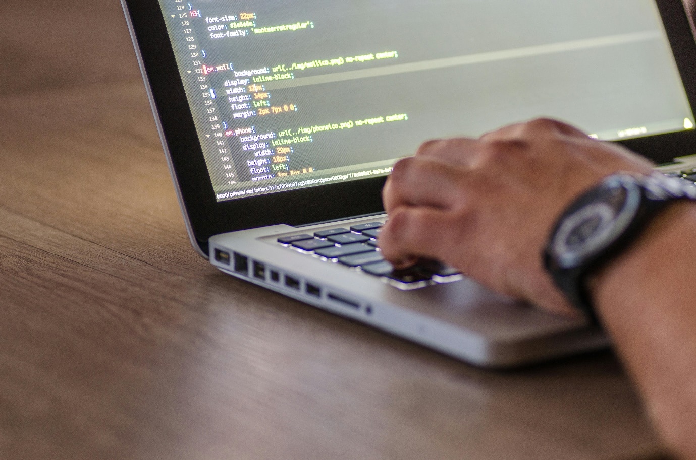 Free A close-up shot of a person coding on a laptop, focusing on the hands and screen. Stock Photo