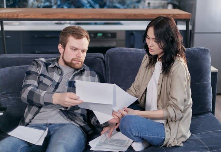 Free Asian woman and Caucasian man discussing taxes on couch. Stock Photo