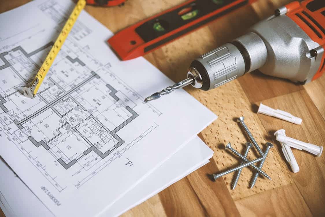 Free Close-up of construction blueprint with tools like drill and screws on a wooden table. Stock Photo