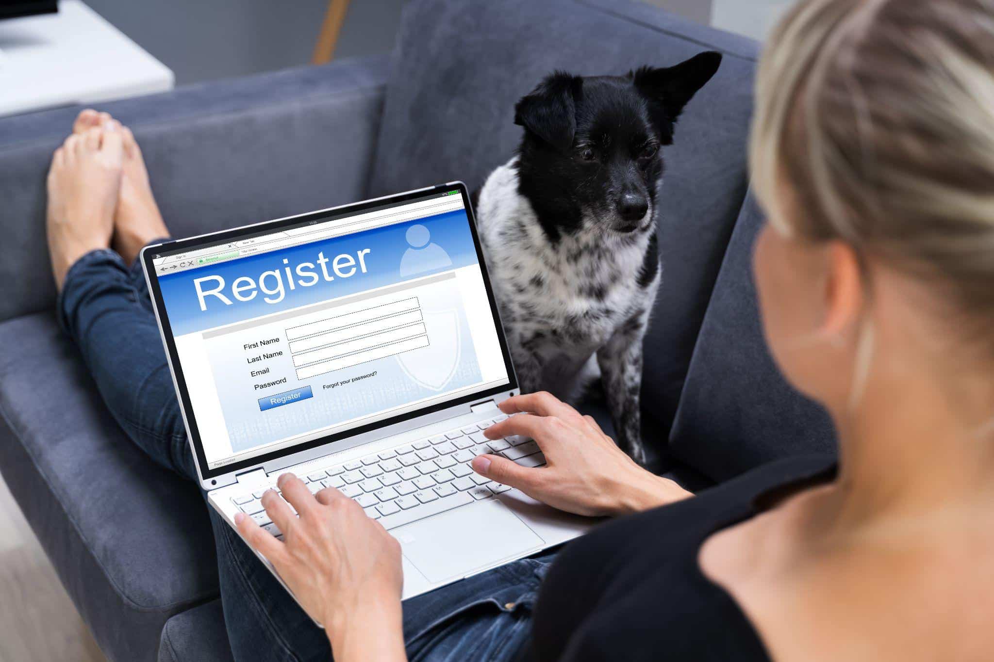 A woman registering online for an ESA letter while her dog sits beside her on the couch